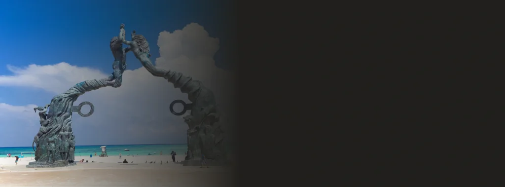 Famous beachfront sculpture and blue skies representing dental tourism in a coastal destination.