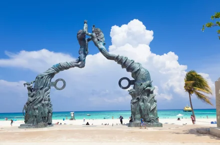 Famous beachfront sculpture and blue skies representing dental tourism in a coastal destination.