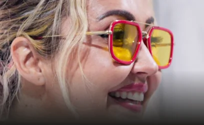 Close-up profile of a smiling female patient showcasing her bright teeth after a cosmetic dental treatment, wearing pink and yellow sunglasses