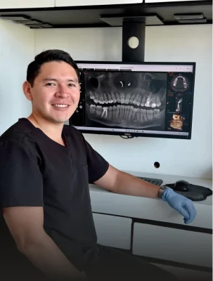 Smiling dentist reviewing digital 3D x-rays on a monitor during a personalized cosmetic dentistry consultation.
